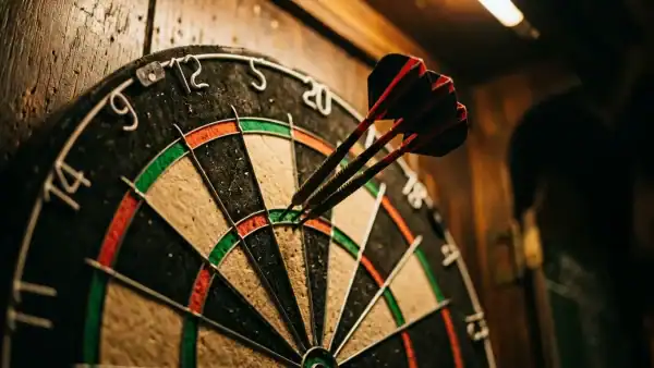 Three darts grouped in a dartboard segment under warm pub lighting with shallow depth of field