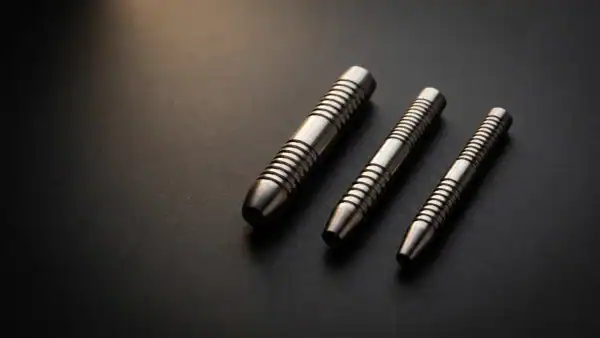 Three tungsten dart barrels of different widths on dark charcoal surface representing 80 90 and 95 percent tungsten