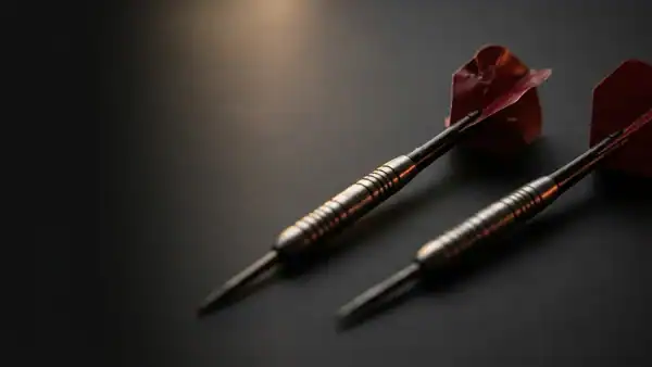 Two darts on a dark surface - one with damaged flights, one with pristine flights