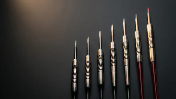 Seven darts arranged in ascending hierarchy representing the PDC Order of Merit rankings system